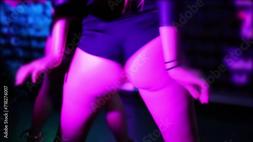 Close up booty woman dancing on stage of club next to other.