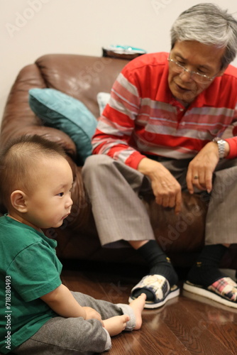 An Asian grandfather and his grandson. An elderly grandfather sternly scolds his grandson, who is showing a lack of interest in the disciplinary words.