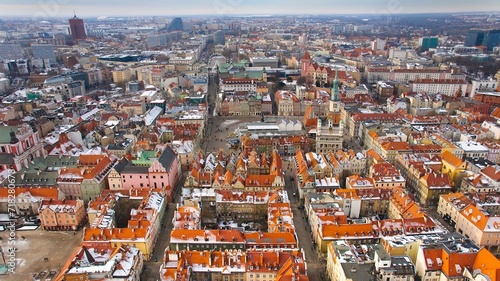 Aerial view of Poznan's historic market square in winter, showcasing the charming old townhouses adjacent to the square. The drone captures the city's architectural heritage under a winter sky. © Grzegorz