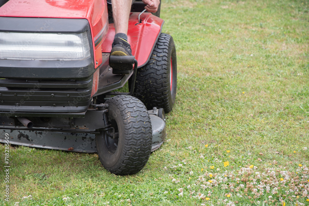 Lawn mower mows the grass, a middle-aged male gardener works on a mini tractor Lawn mower mows the grass, a middle-aged male gardener works on a mini tractor