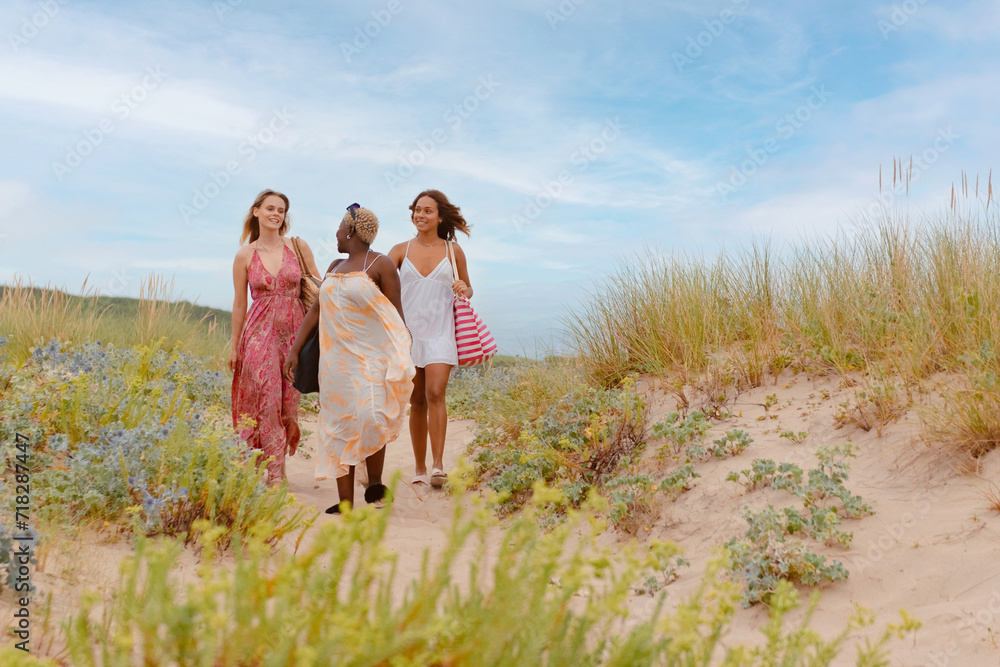 multiracial group of three young girls walking together on the beach during a summer trip. multiracial group of three young girls walking together on the beach during a summer trip.