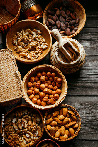 Handmade wicker baskets and wood plates with almonds, hazelnut, walnut. Vintage food background with different nuts and baskets.