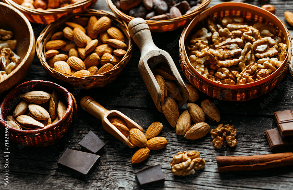 Wood scoops with almods almond between handmade wicker baskets and wood plates with almonds, hazelnut, walnut. Vintage food background with different nuts and baskets. Wood scoops with almods almond between handmade wicker baskets and wood plates with almonds, hazelnut, walnut. Vintage food background with different nuts and baskets.