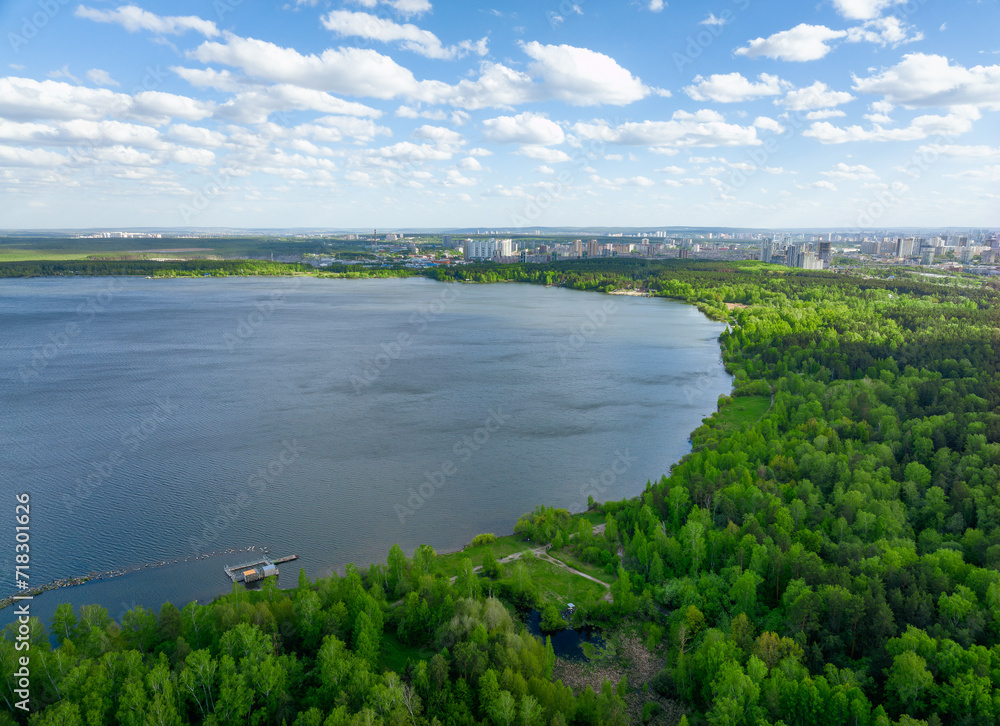 Big lake with green shores in bright sun light and city on horizon, aerial landscape. Recreation concept. Aerial view Big lake with green shores in bright sun light and city on horizon, aerial landscape. Recreation concept. Aerial view