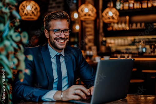 A professional businessman sitting at his desk, exuding confidence and happiness as he works on his laptop in his stylish office, adorned with modern furniture and sporting a pair of sleek glasses