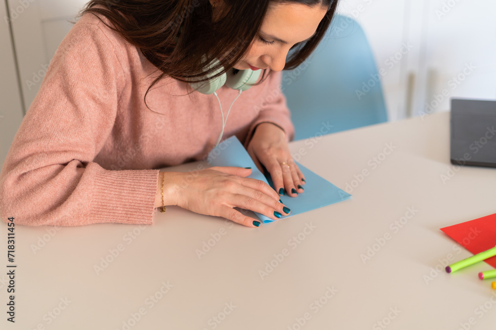 A focused woman wearing headphones crafts with paper, possibly preparing an April Fools' prank.April Fools' Day Crafting Concept