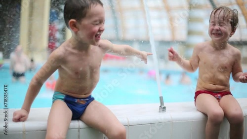 Two boys playing with a jet of water on the pool edge in water park photo