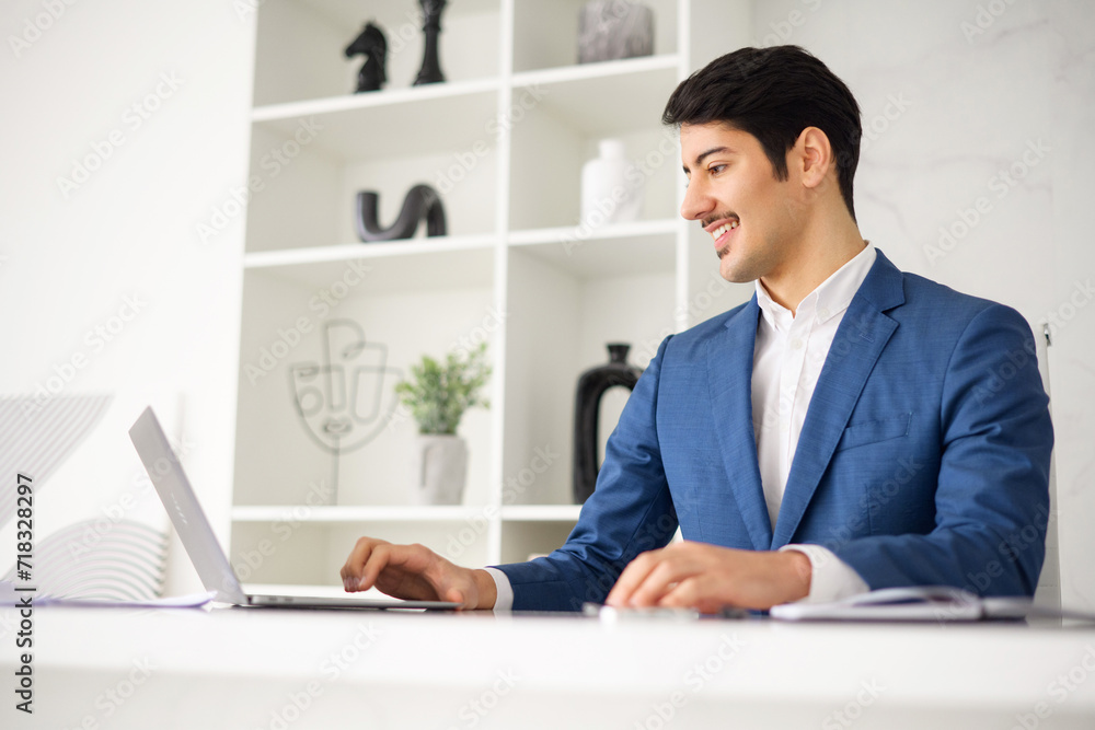 An attentive Hispanic businessman engages with his laptop, typing away in an environment that reflects the contemporary intersection of business and technology, side view An attentive Hispanic businessman engages with his laptop, typing away in an environment that reflects the contemporary intersection of business and technology, side view
