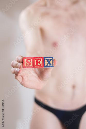 A man in underwear holding blocks in his hand that spell out the word LOVE