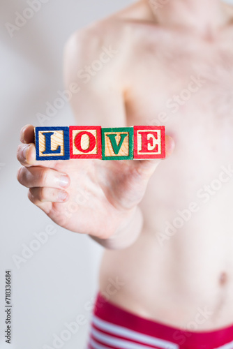 A man in underwear holding blocks in his hand that spell out the word LOVE