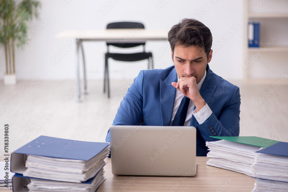 Young male employee and too much work in the office Young male employee and too much work in the office