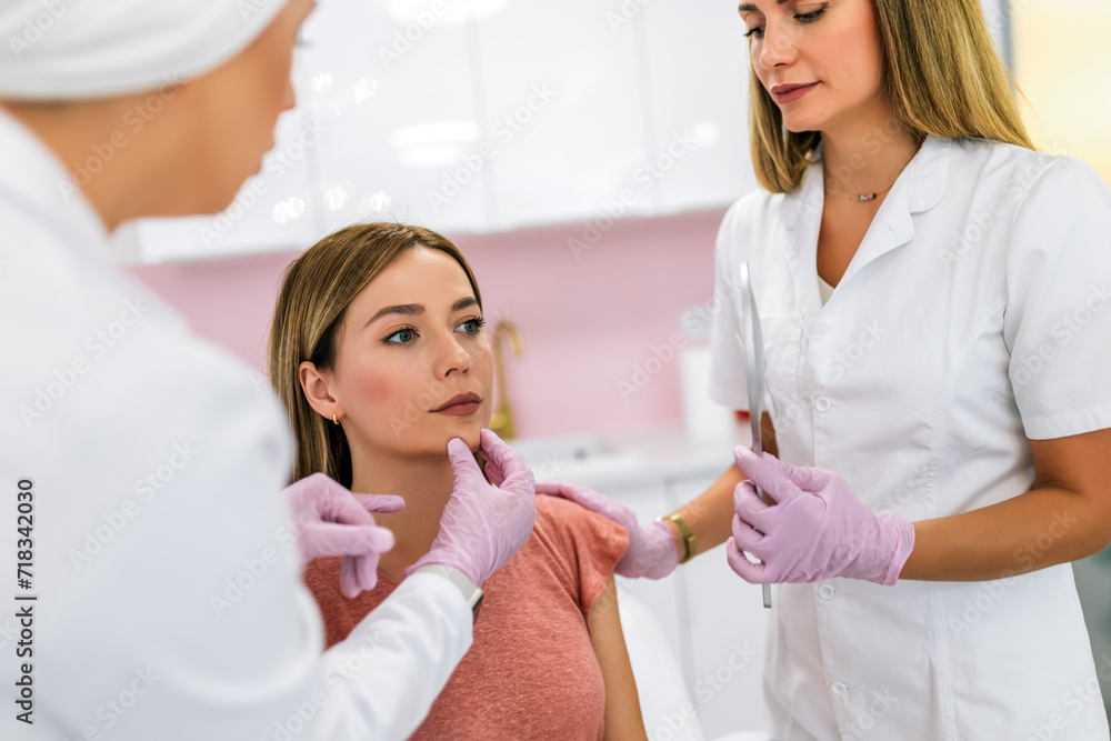 A doctor examines the patient before the aesthetic procedures. The patient looks at herself and tells her what she wants to change. A doctor examines the patient before the aesthetic procedures. The patient looks at herself and tells her what she wants to change.