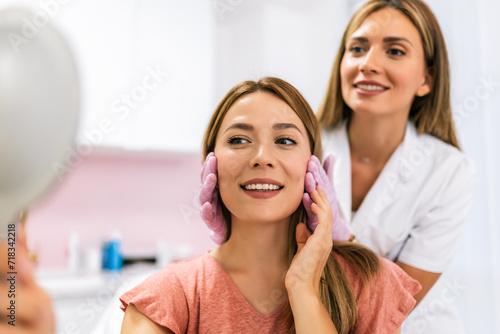 A doctor examines the patient before the aesthetic procedures. The patient looks at herself and tells her what she wants to change. photo