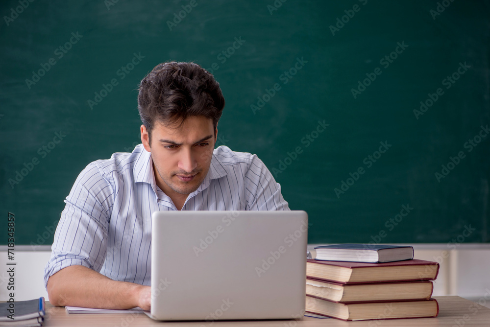 Young male teacher in front of green board Young male teacher in front of green board