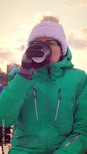 Adorable woman finishes her coffee from paper cup turns it over slaps bottom checking remains of drink in public park, vertical shot
