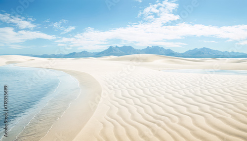 A sandy beach with ripples in the sand a body of water and mountains in the distance