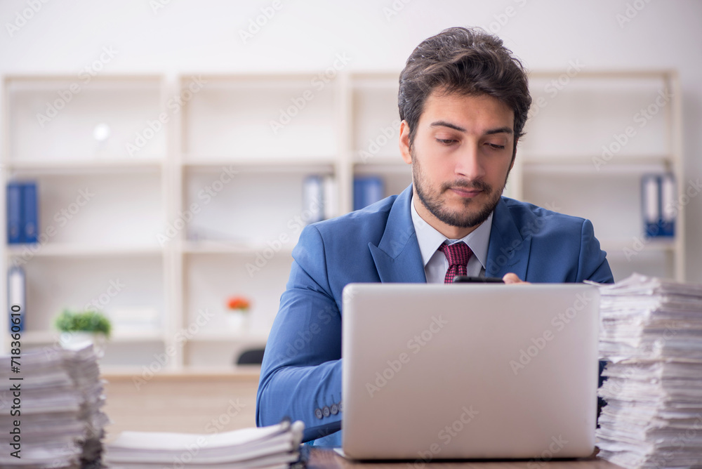 Young male employee and too much work in the office Young male employee and too much work in the office