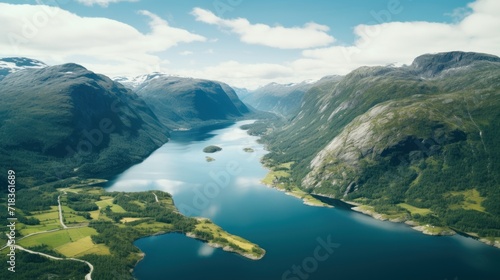 an aerial view of a large body of water surrounded by lush green hills and a blue sky with white clouds.