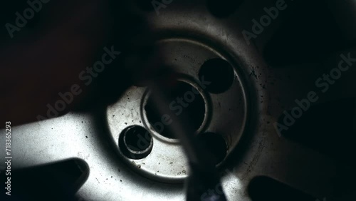 Filming of unscrewing nuts from a wheel in a repair shop. Close-up shooting with flashlight illumination. photo