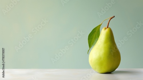  a pear with a green leaf sticking out of it's side sitting on a table with a green wall in the background.