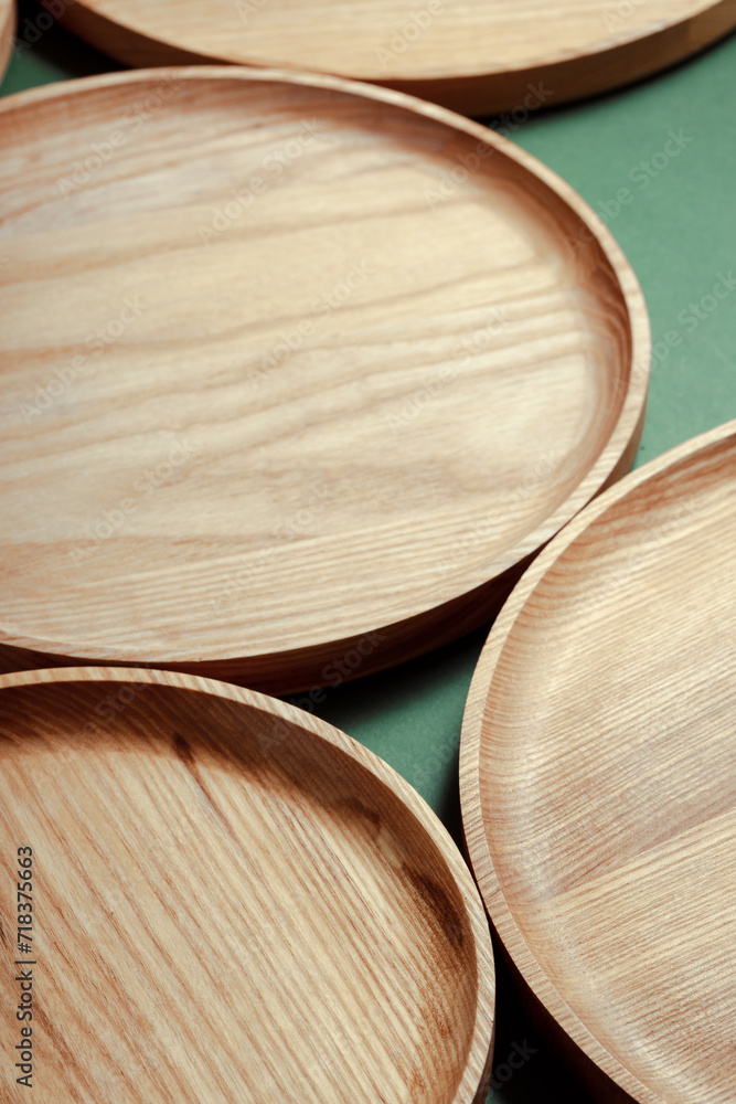 Wooden flat plates on a green background. The concept of ecological tableware. Products for modern kitchen. Zero emissions.