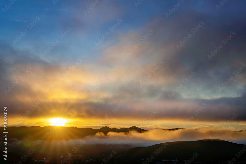 sunburst on horizon at sunset, in mountains, with sun