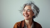 Portrait of a cheerful elderly woman with stylish gray hair, laughing softly, light and airy background. Natural beauty, lively and content expression