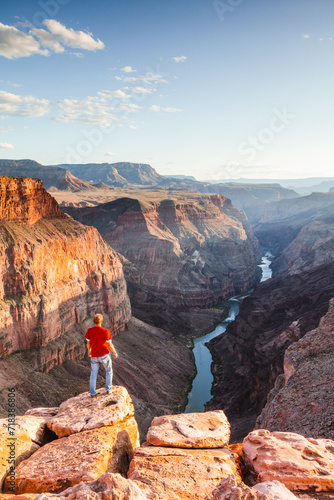 Man standing on the edge of the Grand Canyon at sunset, Arizona, United States