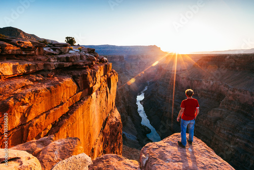 Tourist standing on the edge of the Grand Canyon at sunrise, Arizona, United States