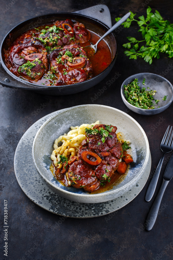 Traditionelles geschmortes italienisches Ossobuco alla Milanese mit Gremolata und Spätzle serviert in einer Nordic Design Schale Traditionelles geschmortes italienisches Ossobuco alla Milanese mit Gremolata und Spätzle serviert in einer Nordic Design Schale