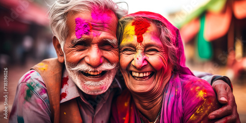 older couple with colorful powders on their faces smiling and celebrating Holi festival - festival of colours, love and spring