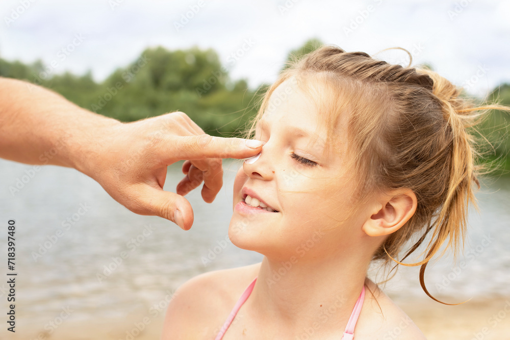 close-up portrait happy girls on the beach during summer holidays. parent applies sunscreen to child. children play on a lake surrounded by green forest on weekends close-up portrait happy girls on the beach during summer holidays. parent applies sunscreen to child. children play on a lake surrounded by green forest on weekends