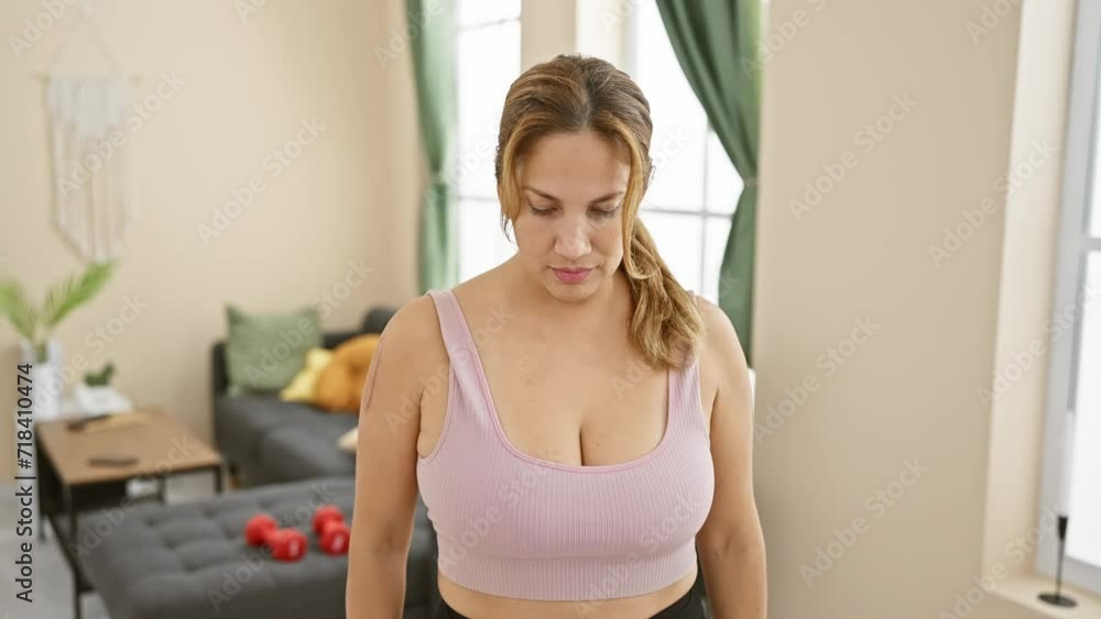 Contemplative latina woman standing in a cozy living room, exuding tranquility and introspection Contemplative latina woman standing in a cozy living room, exuding tranquility and introspection