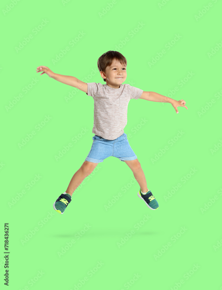 Happy boy jumping on light green background, full length portrait Happy boy jumping on light green background, full length portrait