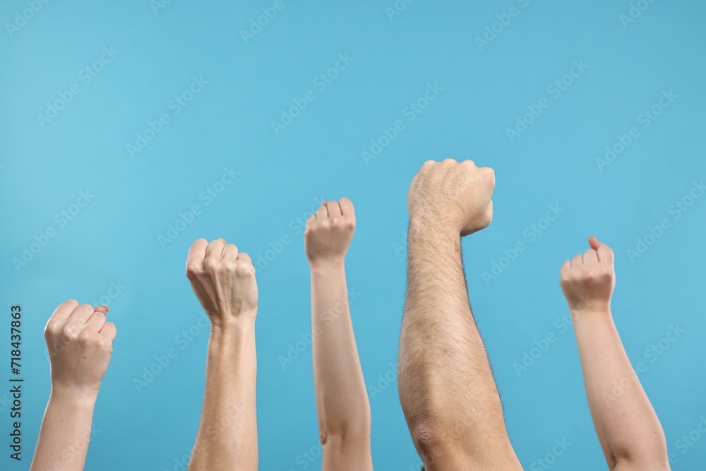 Strike. People showing clenched fists on light blue background, closeup Strike. People showing clenched fists on light blue background, closeup