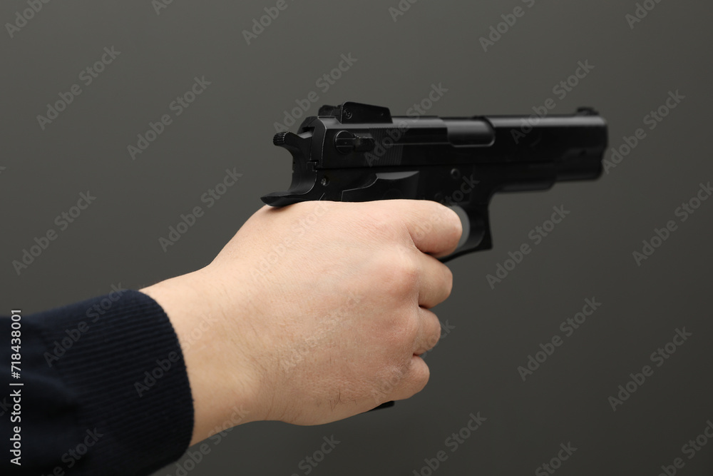 Man with handgun on dark gray background, closeup Man with handgun on dark gray background, closeup
