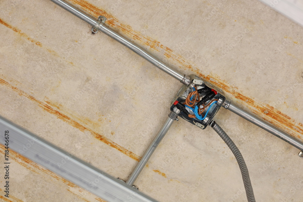 Wire Nut connects electrical wires in a junction box. Plastic insulating clamps encase twisted wire connections in metal distribution boxes with conduit pipes on concrete walls. Selective focus