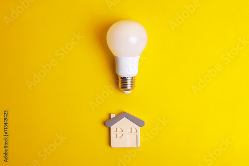 White light bulb and a house symbol on yellow background. Concept saving energy with LED lamp at home photo