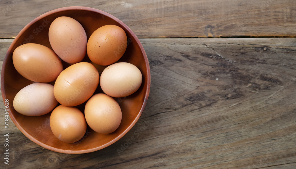 Fresh eggs arranged in a wooden bowl on a wooden table in an organic farm with Copy space - top view. Fresh eggs arranged in a wooden bowl on a wooden table in an organic farm with Copy space - top view.