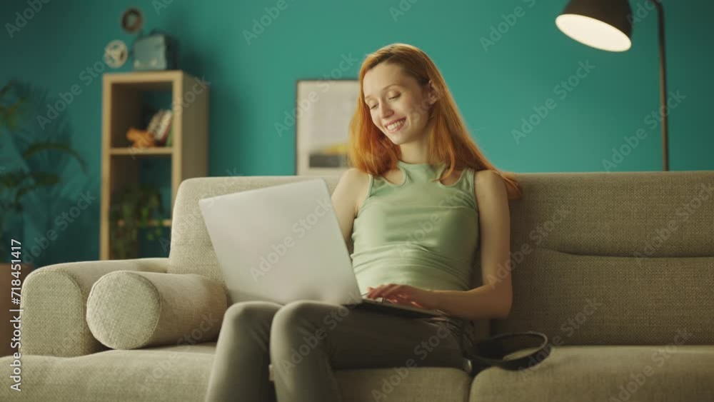 A caucasian woman working remotely on her laptop. A girl doing business from home on the sofa A caucasian woman working remotely on her laptop. A girl doing business from home on the sofa
