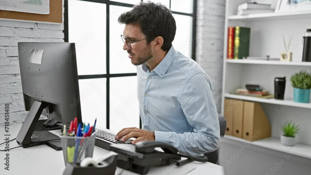 Young hispanic man with beard working at computer in modern office setting Young hispanic man with beard working at computer in modern office setting