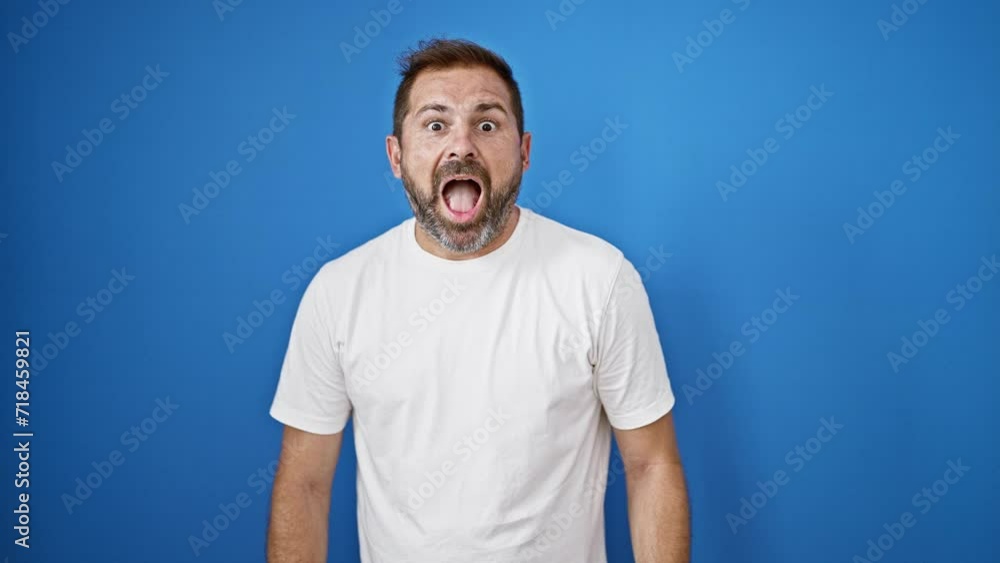 Mature man with grey hair in a white shirt expressing surprise against a blue background outdoors. Mature man with grey hair in a white shirt expressing surprise against a blue background outdoors.