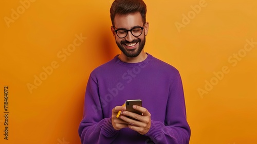 cheerful man in eyeglasses and purple sweater using smartphone on orange background, texting © Jennifer