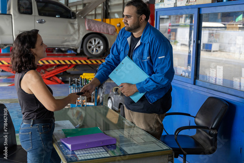 A very attractive women get her car back at the counter of the tire and car service workshop shaking hand with mechanical employee of the service and looks very satisfied and happy. Selective Focus.