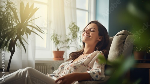 A Happy woman sitting in comfortable chair in home design, relaxing, breathing fresh air. A smiling young female tenant or a tenant relaxing in an armchair relieves negative emotions photo
