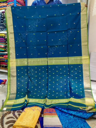 Maheshwari saris in a textile shop, displayed in front of customers. Maheshwar, Madhya Pradesh, India. photo