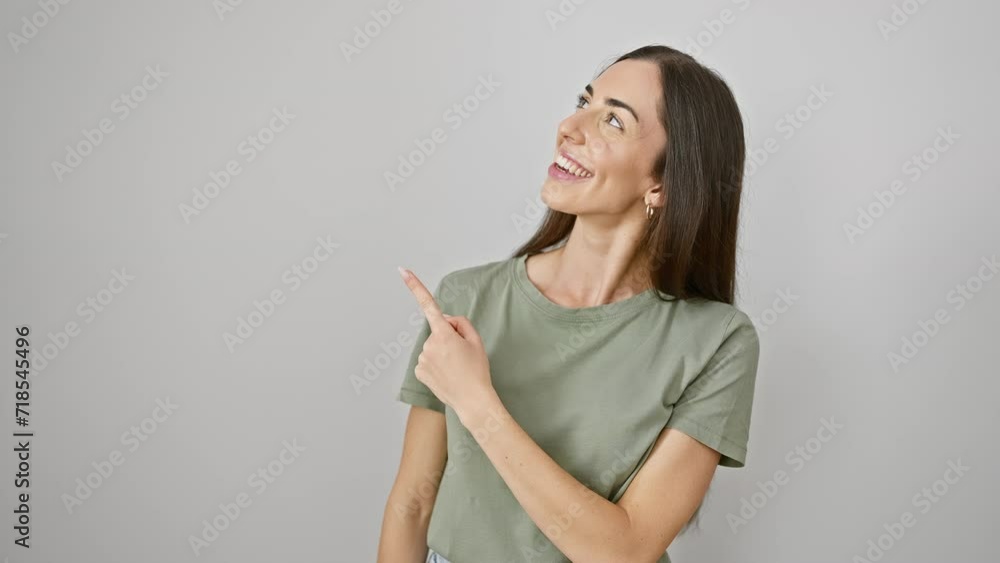 Cheerful young hispanic woman, donned in casual clothes,brandishes a bright smile. hand pointing finger up on the side, against a background of beautiful isolated white. a splendid welcome! Cheerful young hispanic woman, donned in casual clothes,brandishes a bright smile. hand pointing finger up on the side, against a background of beautiful isolated white. a splendid welcome!