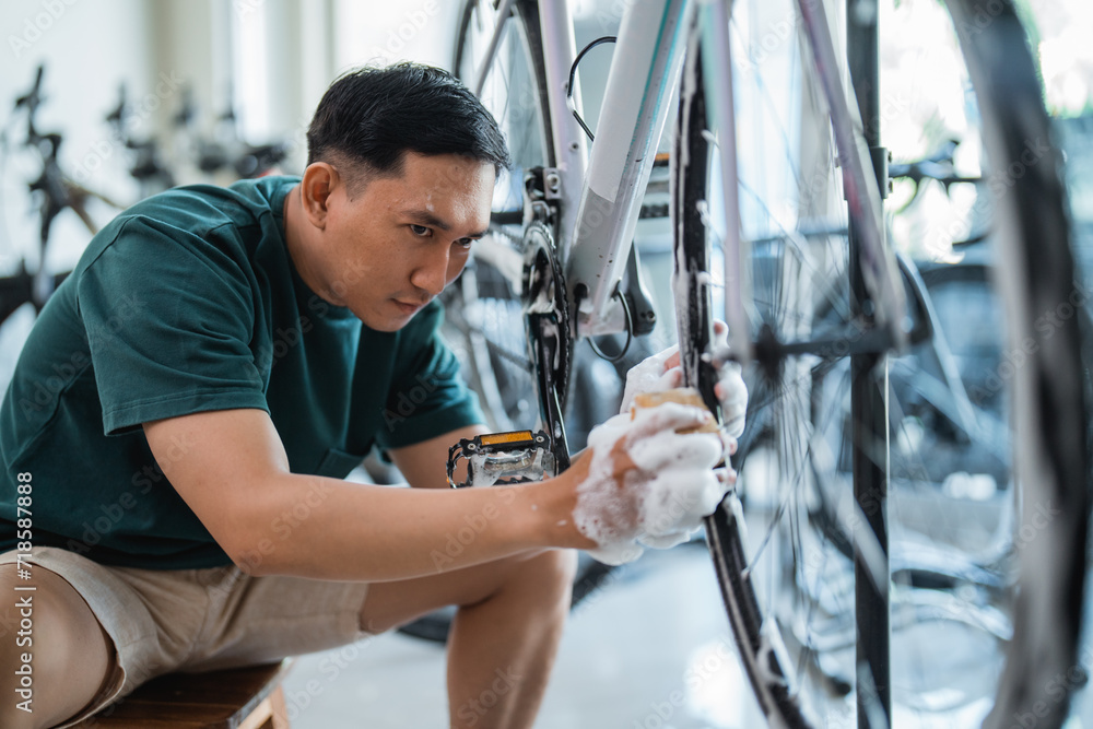 young man washing bicycle wheels with foaming soap at a bicycle shop