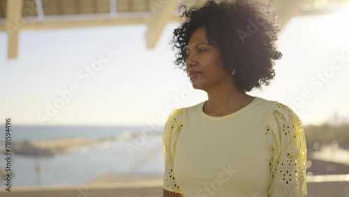 Video of an African woman standing at a viewpoint with the breeze gently moving her curly hair