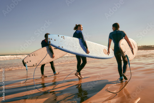 Canvas Print Group of friends with surfboards entering towards ocean for surfing on waves